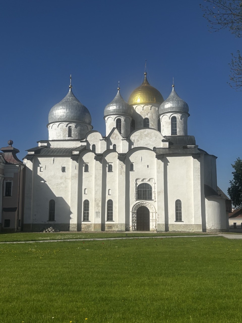 Женщина созерцает древний белокаменный храм в Великом Новгороде